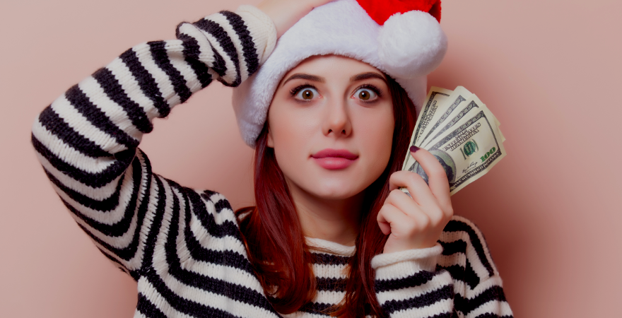 Young woman in Santa cap holding money in one hand