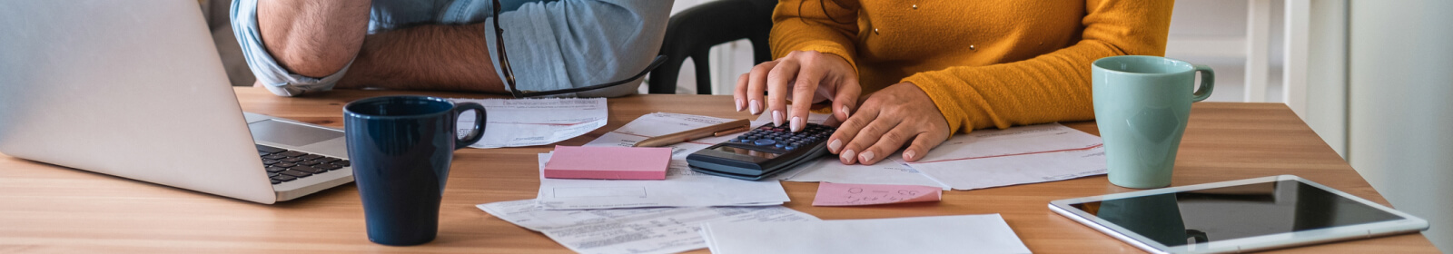 Man and woman sitting at table working on calculator while budgeting 