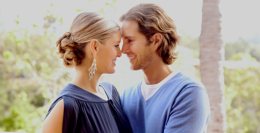 Young couple faces each other smiling. 