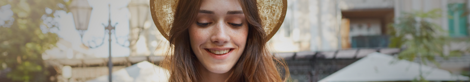 Young woman in a hat smiling.